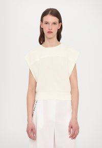 Strikket kremfarget topp med korte, strukturerte ermer og ribbestruktur. Har en cropped design med en glatt finish i kanten.