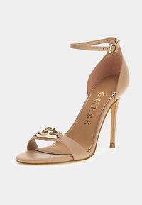 Beige korkeakorkoiset sandaalit nilkkahihnalla, avonaisella varpaalla ja Kultainen metallilogo koriste etuhihnassa, brändätystä sisäpohjasta "GUESS".