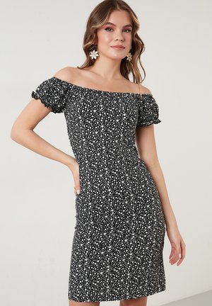 Black floral off-the-shoulder dress with short puff sleeves, fitted bodice, and stretch fabric. Features white flower patterns throughout.