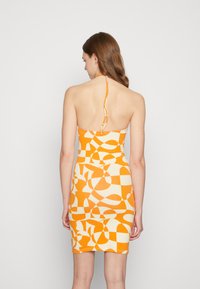 Vestido bodycon com um padrão geométrico em laranja e creme, design com decote halter e uma silhueta ajustada que realça as curvas.