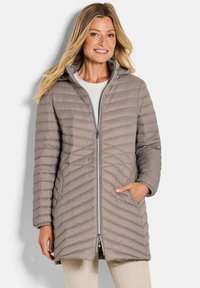 Beige gewatteerde jas met een kap, voorzien van een ritsluiting en diagonale quiltpatroon. Inclusief zijzakken en lange mouwen.