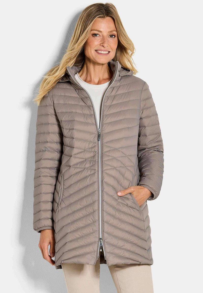 Beige gewatteerde jas met een kap, voorzien van een ritsluiting en diagonale quiltpatroon. Inclusief zijzakken en lange mouwen.