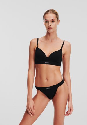 Zwart bh en bijpassende stringset gemaakt van gladde stof. De bh heeft een diepe V-hals en verstelbare bandjes; de string heeft een slanke tailleband.