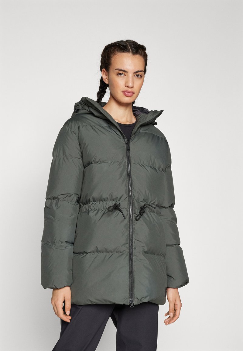 Giacca puffer khaki con zip frontale, vita con cordino elastico e cappuccio. Presenta una texture trapuntata e maniche oversize.