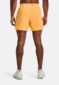Pantalones cortos deportivos para hombres en un brillante color amarillo, fabricados con material ligero, que presentan un diseño liso con detalles en negro a lo largo de los lados.