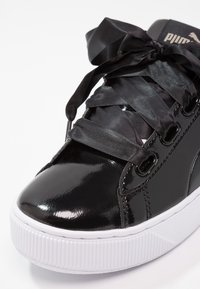 Baskets en cuir verni noir avec un bout arrondi, des lacets en satin et une semelle en caoutchouc blanche avec un design texturé.