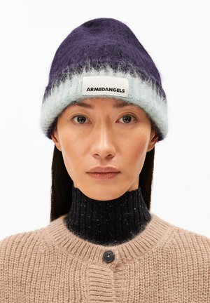 Lila und hellblaue Strickmütze mit flauschiger Textur und einem weißen Label mit der Aufschrift "ARMEDANGELS." Getragen über einem dunklen, gerippten Pulloverkragen.