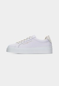 Baskets basses blanches avec lacets beiges et semelle épaisse, avec le logo Tommy Hilfiger sur le côté.
