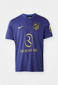 Lilla fotballskjorte med gule detaljer. Har Nike-logo, Atletico Madrid-emblem og "RIYADH AIR" trykt på forsiden. Korte ermer.
