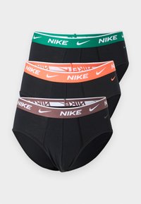 Τρία ζεύγη μαύρα εσώρουχα Nike στοιβαγμένα, το καθένα με διαφορετικό χρωματιστό λάστιχο μέσης: πράσινο, πορτοκαλί και καφέ, με λευκό λογότυπο Nike και κείμενο.