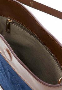 Brown leather tote bag with a blue fabric exterior. Interior features a zippered pocket and beige lining with visible stitching details.