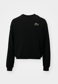 Felpa nera con collo rotondo, maniche lunghe e logo coccodrillo verde ricamato sul petto. Texture morbida e vestibilità comoda.