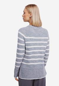 Maglione a righe grigie e bianche con vestibilità rilassata. Orlo a costine e fessure laterali. Texture morbida, collo a giro e spalle leggermente scese.