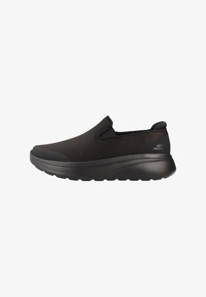 Chaussure de sport noire à enfiler avec tige en mesh, semelle épaisse et rembourrée, et logo Skechers sur le contrefort du talon, conçue pour le confort et le soutien.