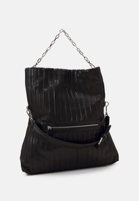 Czarna skórzana torba z pionowym, żłobkowanym wzorem, z srebrnym uchwytem na łańcuszku, regulowanym paskiem na ramię i zamykaną na zamek kieszenią.