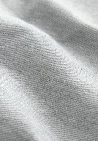 Tessuto grigio con una trama texturizzata, caratterizzato da scanalature orizzontali e un aspetto morbido e liscio. Leggermente puntinato con fili più scuri.