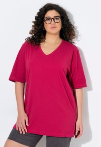 T-shirt a maniche corte con scollo a V in cotone magenta brillante. Vestibilità ampia con spacchi laterali, texture liscia e design rilassato per il massimo comfort.