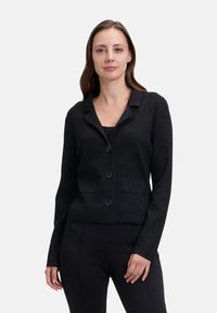 Svart blazer i texturerad tyg med skräddarsydd passform, med krage, fem knappar och två framfickor.