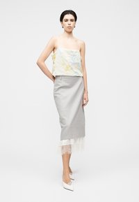 Ελαφρύ cropped τοπ με floral μοτίβο και λεπτές ράντες, συνδυασμένο με γκρι φούστα μέχρι το γόνατο με δαντελένιο τελείωμα στο τελείωμα. Λευκές γόβες.