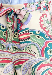 Tissu à motifs avec des designs paisley colorés en vert, rose et lavande. Présente un accent de nœud noué à la taille. Texture lisse.