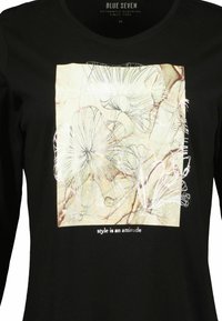 Černá dlouhá rukávová košile s předním potiskem obsahujícím květinové obrysy a text na béžovém pozadí, vyrobená z měkké bavlny.