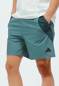 Tyrkysové športové šortky vyrobené z ľahkého materiálu, s čiernymi bočnými akcentmi a logom adidas na ľavej nohe.