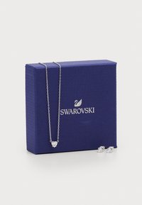 Sudraba kaklarota un auskari, kas izlikti kopā ar karaliski zilo Swarovski box, demonstrējot elegantas rotaslietas.