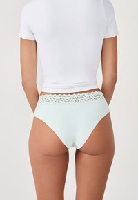 Mutande alta di colore azzurro chiaro con un delicato pizzo lungo la vita. Realizzate in un tessuto morbido e liscio.