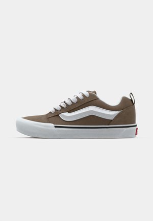 Καφέ σουέτ παπούτσια skate με λευκές κορδόνες, πλευρική ρίγα και λάστιχο σόλα. Διαθέτουν μια μαύρη γραμμή accent και ένα μικρό κόκκινο λογότυπο στη φτέρνα.