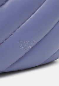 Borsa in pelle viola con texture trapuntata diagonale e cuciture a contrasto. Presenta un logo inciso in modo sottile sul fronte.