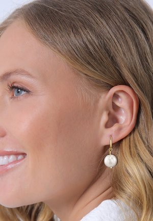 Boucle d'oreille en or avec un pendentif en perle blanche ronde ; texture lisse ; design minimaliste ; convient pour un port décontracté ou élégant.