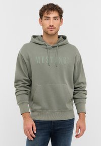 Hoodie vert avec une poche avant, capuche à cordon de serrage et tissu texturé. Présente un logo "MUSTANG" embossé dans une teinte de vert plus claire.