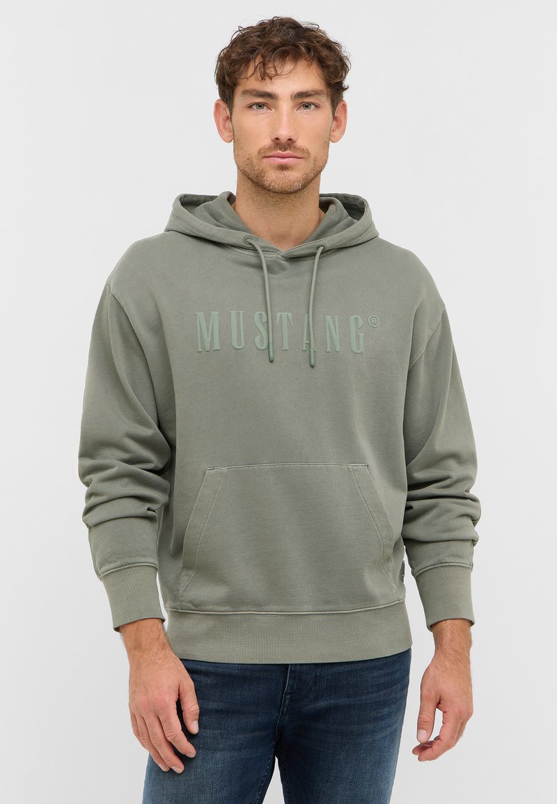 Hoodie vert avec une poche avant, capuche à cordon de serrage et tissu texturé. Présente un logo "MUSTANG" embossé dans une teinte de vert plus claire.