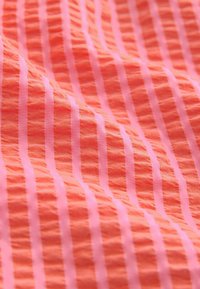 Tela texturizada en color coral con rayas delgadas alternas en rosa. Presenta una superficie arrugada para mayor profundidad e interés.