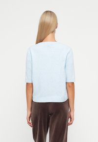 Ανοιχτό μπλε πουλόβερ πλεκτό με κοντά μανίκια, στρογγυλή λαιμόκοψη και ίσια τελειώματα, σε συνδυασμό με καφέ απαλό ύφασμα παντελόνι.