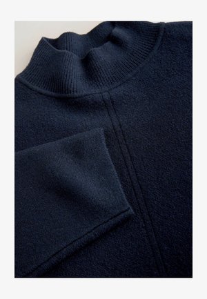 Dunkel marineblauer Strickpullover mit einem Rippenrollkragen und sichtbaren Nahtdetails, die vertikal über die Vorderseite verlaufen.