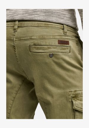 Zielone oliwkowe spodnie cargo z fakturowanej tkaniny, z brązową skórzaną łatą marki, kieszenią tylną oraz metalowym zapięciem.