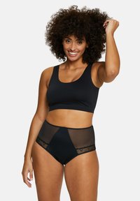 Top court noir sans couture avec bretelles larges associé à des culottes taille haute présentant des panneaux en maille et des accents en dentelle. Les deux pièces ont une texture lisse.