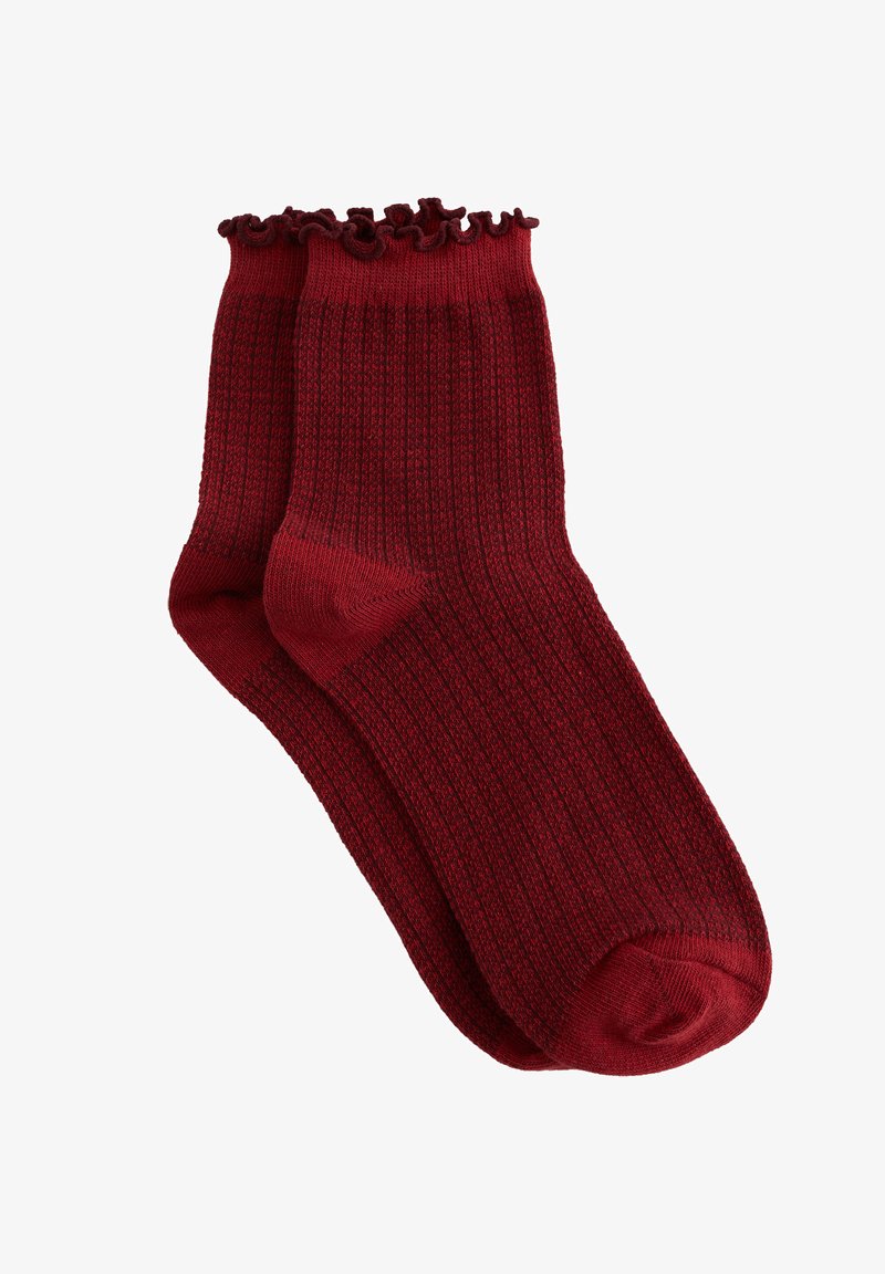 Calcetines rojos con canalé y un puño fruncido en la parte superior. Hechos de un material suave, presentan un patrón texturizado en toda la superficie.