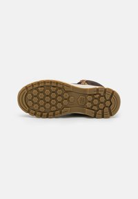 Semelle de chaussure d'extérieur marron avec un caoutchouc texturé présentant des motifs hexagonaux pour une meilleure adhérence et une couleur contrastante beige.