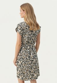 Robe fleurie à manches courtes, fond crème avec des motifs noirs et moutarde. Taille cintrée, longueur genou, texture lisse.