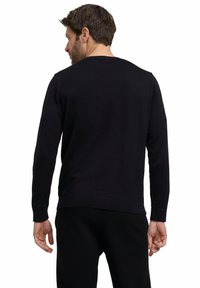 Schwarzer Strickpullover mit langen Ärmeln, Rundhalsausschnitt sowie gerippten Bündchen und Saum. Der Stoff wirkt glatt und weich.