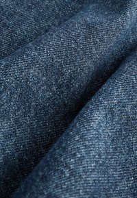 Denim-kangas tummansinisellä värillä, hienolla tekstuurilla ja hienovaraisilla sävyeroilla, esittäen lähikuvan kudotusta materiaalista.