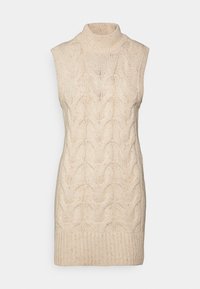 Maglione senza maniche color crema con colletto a lupetto, caratterizzato da un motivo a trecce e orlo a costine. Morbida texture con puntini sparsi.