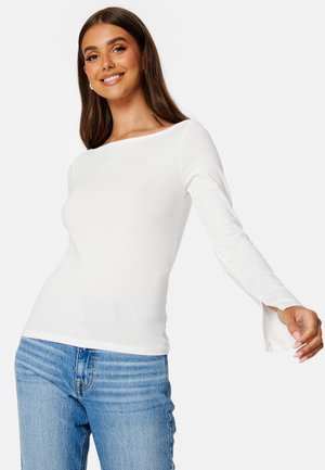Witte langemouwen top met een brede bateauhals en uitlopende mouwen, gecombineerd met lichtblauwe denimjeans. Gladde textuur en aangesloten ontwerp.