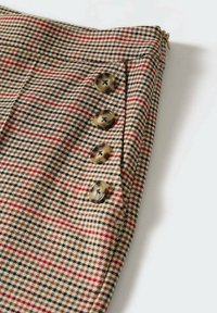 Geruite stof in beigetinten, bruin, rood en zwart. Heeft vier ronde knopen aan de zijkant en een ritssluiting aan de bovenkant.