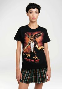 Black cotton T-shirt featuring a graphic of a creature from "Gremlins" in vibrant colors, with a round neckline and short sleeves.