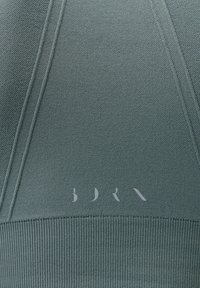 Zelená mikina se strukturovanou tkaninou, žebrovaným lemem a decentním potiskem loga. Obsahuje výrazné švy a strukturovaný design.