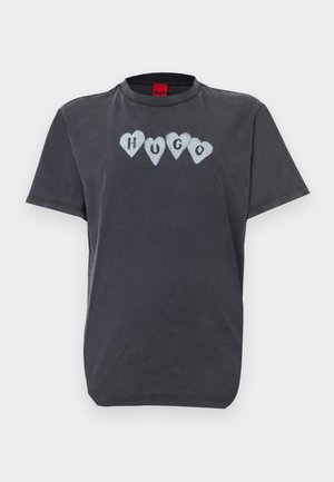 Black cotton t-shirt featuring a crew neck, short sleeves, and a printed design of light blue hearts with "HUGO" in black in the center.