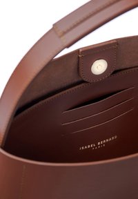 Braunes Lederhandtaschen-Innenleben mit glatter Textur, ausgestattet mit einem Druckverschluss, Kartenfächern und geprägtem Markennamen "ISABEL BERNARD PARIS."